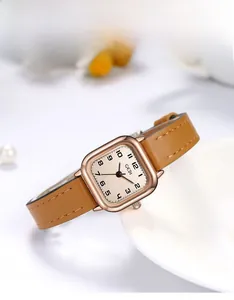 Macro detail of elegant square quartz watch with brown leather strap and rose gold case