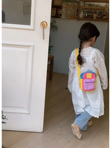 Toddler crossbody bag with colorful panels and adjustable strap worn by child model