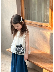 Detail of child wearing a floral mini chain bag with a black bow in natural sunlight