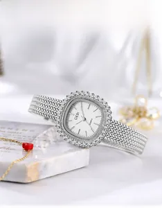 Detalle de reloj de cuarzo cuadrado plateado con bisel de cristal y correa de metal tejido