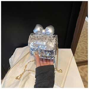 Close-up of silver sequin mini bag with metallic bow and gold chain strap detail