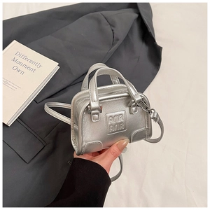 Gros plan du mini sac argenté texturé avec logo embossé et poignée de transport courte