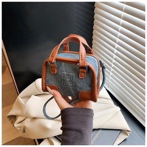 Détail d'un mini sac en denim avec bordure en cuir marron et logo de lettres en relief
