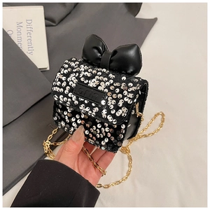 Detailed view of children's sequin mini bag featuring black bow and gold chain strap