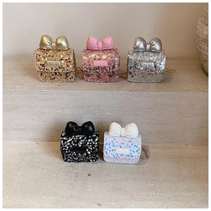 Detail of five sequin mini bags with bows on stone steps showing colors and textures