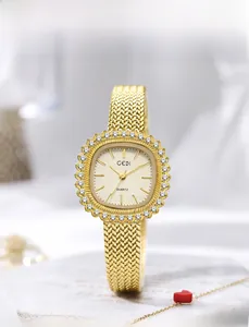 Primer plano de reloj cuadrado dorado con bisel de cristal sobre base de mármol