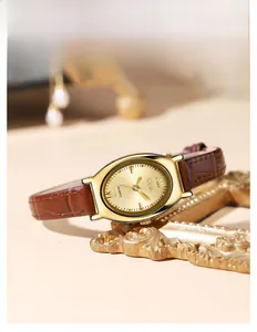 Détail d'une montre quartz tonneau dorée avec bracelet en cuir marron motif crocodile