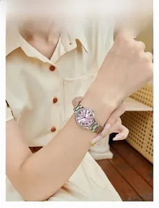 Close-up of a silver steel watch with pink dial and blue hands worn on a lady's wrist
