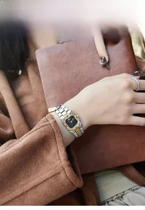 Close-up of rectangular black dial and two-tone metal band on wrist with wool coat