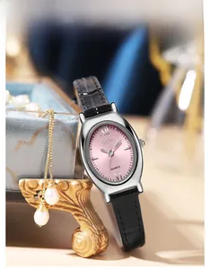 Vue macro d'une montre GEDI ovale avec cadran rose à côté d'une boîte à bijoux en perles