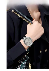 Close-up of a silver square watch with grey dial and date display on a female wrist