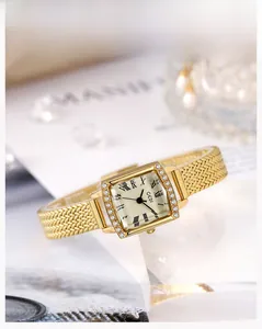 Détail d'une montre carrée dorée avec bracelet en maille et lunette sertie de cristaux