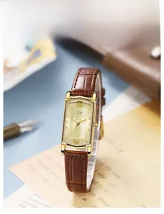 Detail of vintage rectangular gold watch with textured dial and brown leather strap