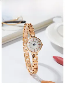 Rose gold quartz watch for women with white dial on a desk with a coffee cup