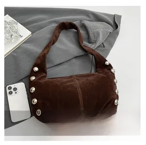 Dettaglio delle borchie argentate e texture scamosciata di una borsa hobo marrone scuro
