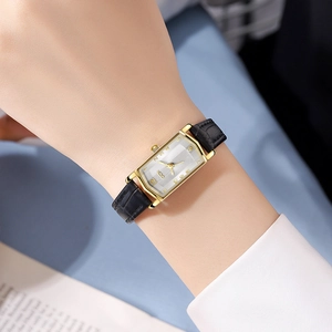 Elegant vintage rectangle women watch with golden case and black leather strap worn on wrist