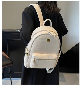 Detail of cream woven textured backpack with gold zippers and rivets on a model