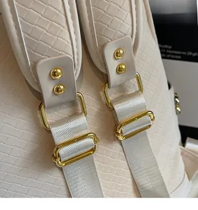 Detail of white woven leather backpack with polished gold hardware and rivets