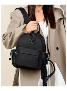 Detail of black nylon travel backpack with front zipper pocket and reinforced top handle