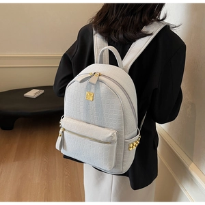 Detailed shot of white crocodile texture backpack with gold rivets and metallic hardware