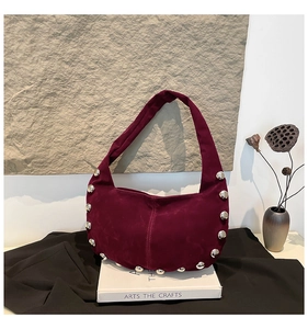 Dettaglio della borsa hobo in camoscio bordeaux con borchie metalliche su libri