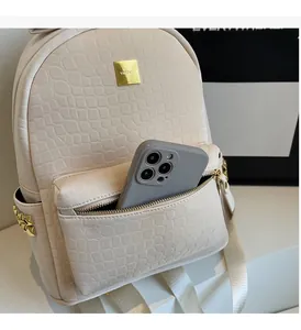 Detail of cream crocodile textured backpack with gold studs and VDPALO metal logo plate