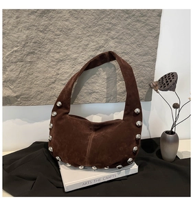 Dettaglio borchie in metallo argento su borsa hobo in pelle scamosciata marrone