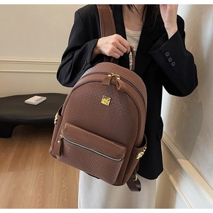Detail of coffee brown backpack featuring woven texture and gold metal logo plaque
