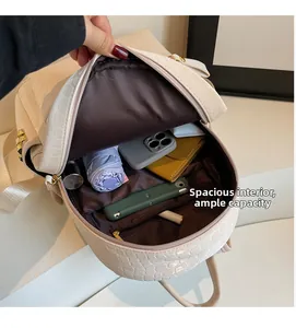 Detail view of the spacious interior and compartments of this cream crocodile embossed backpack