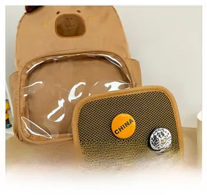 Detail showing brown cartoon backpack with clear PVC front pocket and DIY badges