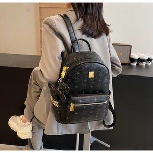 Detail of cute cartoon bear print on black faux leather backpack with gold metal zippers