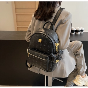 Detail of black printed backpack with golden hardware and cute bear charm accessory
