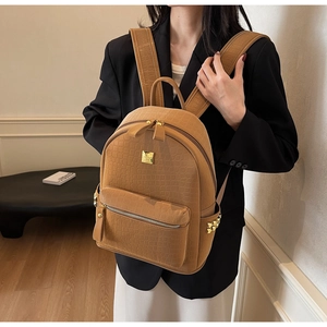 Detail of brown crocodile pattern backpack with gold pyramid studs and metallic logo