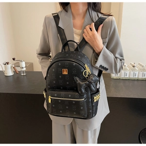 Detail of black leather backpack featuring cartoon prints, gold studs and puppy charm
