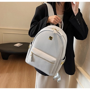 Detail of woven texture backpack with gold zipper and metal hardware accents