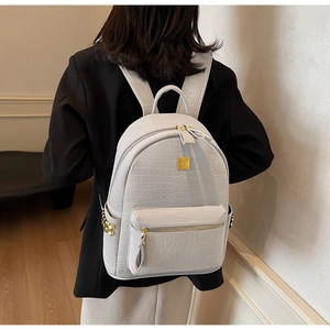 Close-up of white crocodile pattern faux leather backpack with gold metal plate and zipper