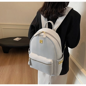 Detailed view of woven texture and gold metal hardware on a white leather backpack