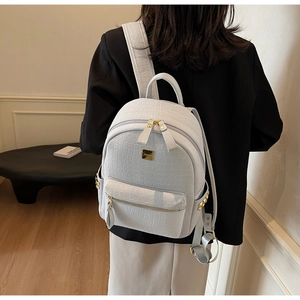 Detail of light blue faux crocodile leather backpack with gold pyramid studs and logo plate