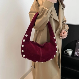 Borsa hobo in pelle scamosciata bordeaux con grandi borchie argentate indossata a spalla