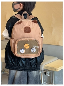 Detail view of brown capybara toddler backpack with transparent PVC front pocket and badges
