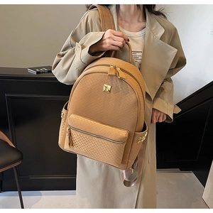 Detail of woven texture camel leather backpack with gold studs and zipper details