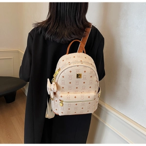 Detail of cute bear print and bow charm on a cream faux leather backpack with gold zippers