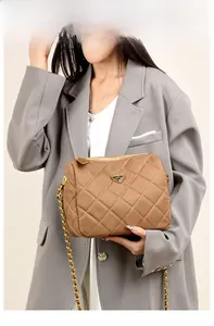 Gros plan d'un sac bandoulière marron matelassé avec chaîne dorée sur blazer gris