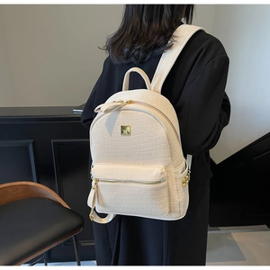 Close-up of cream white crocodile texture backpack featuring gold metallic zipper details