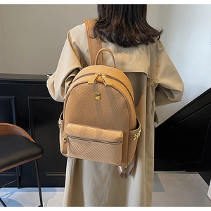 Detail of light brown textured backpack with woven pattern and gold metal hardware