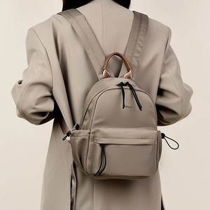 Detail of taupe travel backpack featuring side drawstring pockets and leather handle