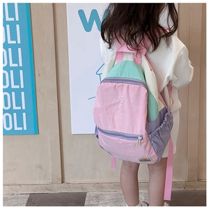 Rear view of kid wearing a pastel color-block waterproof backpack with multiple pockets