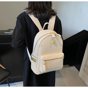 Detail of cream beige crocodile pattern backpack with gold studs on the side