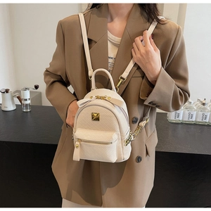 Chic mini cream woven backpack with bow detail and gold chain straps on a model