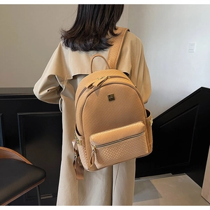 Rear view of a camel woven texture backpack worn by a model in a modern interior setting